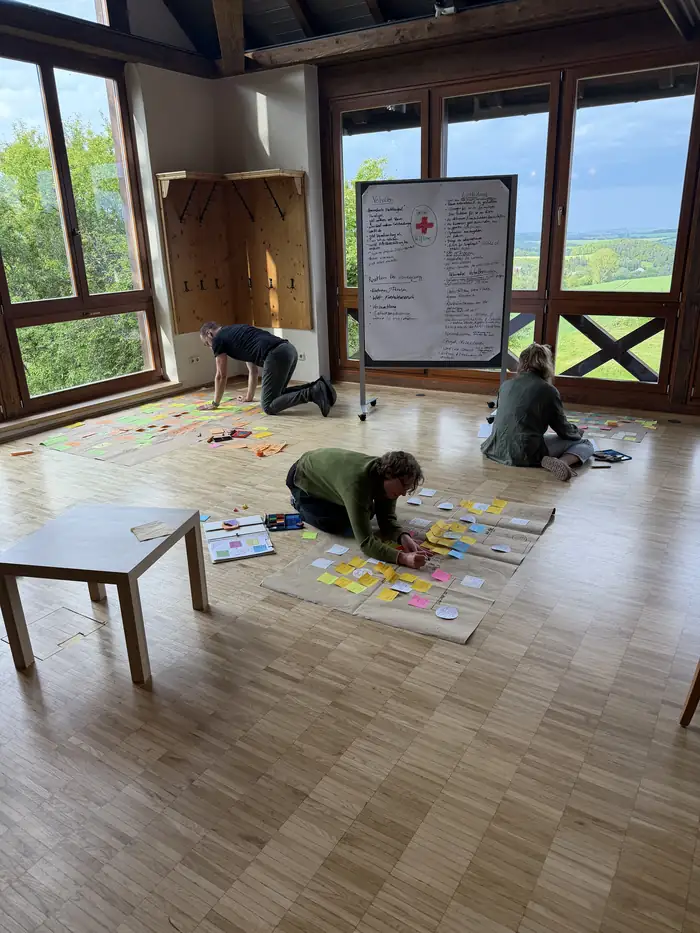 Teilnehmende arbeiten im Seminarhaus am Boden an ihren Genogrammen, Modul Selbstreflexion