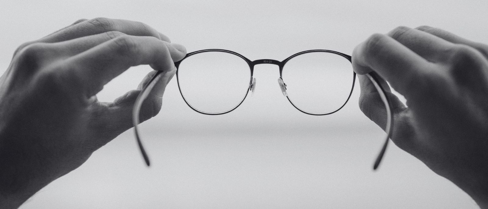 Zwei Hände halten eine Brille – Symbol für klare Sicht, Fokus und Vision